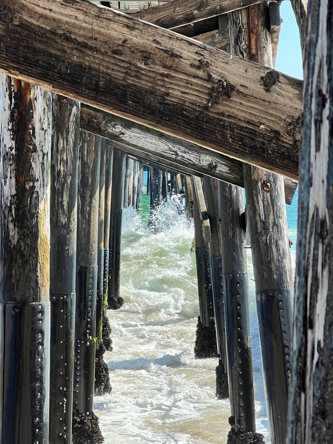 Surf rushing between the wooden pilings beneath the pier